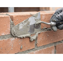 Maçon jointoyant un mur de briques avec une truelle