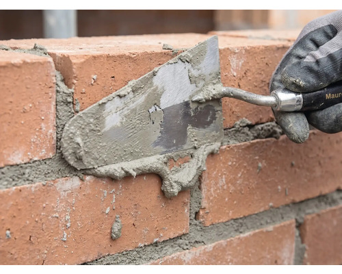 Maçon jointoyant un mur de briques avec une truelle