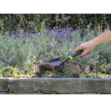 Une personne utilise une petite pelle de jardin pour creuser dans une plate-bande.