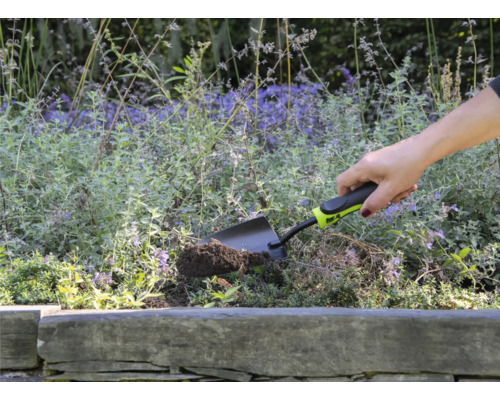 Une personne utilise une petite pelle de jardin pour creuser dans une plate-bande.
