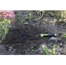 Rateau de jardin dans le sol à côté d'une fleur
