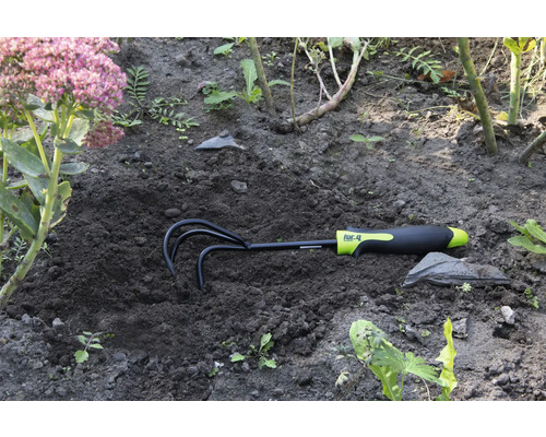 Rateau de jardin dans le sol à côté d'une fleur