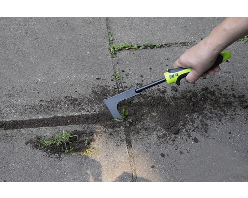 Eine Person entfernt Unkraut mit einem Fugenkratzer auf einer gepflasterten Fläche.