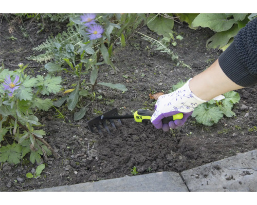 Person verwendet einen kleinen Rechen zur Gartenarbeit