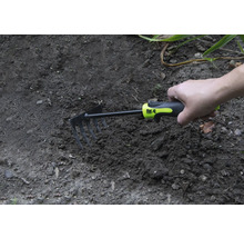 Hand hält eine kleine Harke im Gartenboden