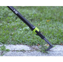 Grattoir à joints for_q fitconnect éliminant les mauvaises herbes d un joint de pavage sur une dalle de chemin à côté d une pelouse.