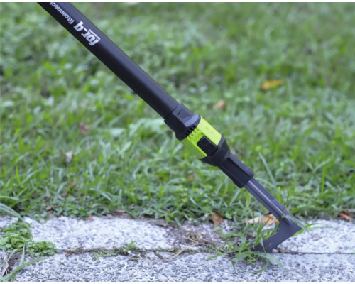 Grattoir à joints for_q fitconnect éliminant les mauvaises herbes d un joint de pavage sur une dalle de chemin à côté d une pelouse.