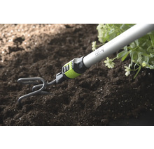 Griffe de jardin avec manche ameublissant la terre à côté de plantes.