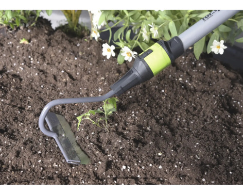 Binette de jardin en métal lors du travail de la terre à côté d une plante.