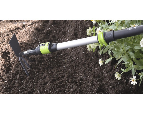 Serfouette for_q avec manche télescopique utilisée dans la terre à côté de fleurs lors de travaux de jardinage.