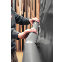 Hände fassen eine graue Teichfolie aus Kunststoff an.