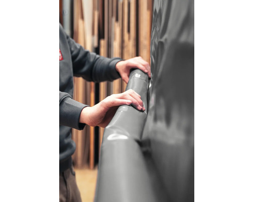 Hände fassen eine graue Teichfolie aus Kunststoff an.