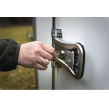 Une main insère une clé métallique dans la serrure du verrou de porte d'une remorque.
