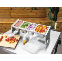 Station de préparation Tenneker en acier inoxydable avec quatre bacs Gastronorm sur une table en métal, remplis de sauces et de légumes pour grillades.