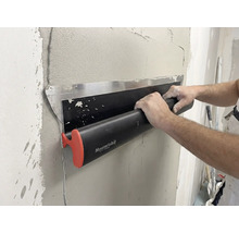 Eine Person verwendet eine Maurerlob Flächenspachtel, um feuchten Putz auf einer Wand glattzustreichen.