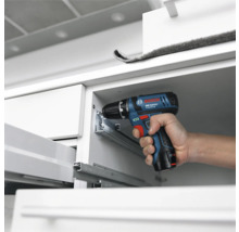 Bosch Professional Akku-Bohrschrauber bei der Montage von Metall-Schubladenschienen in einem weissen Schrank.