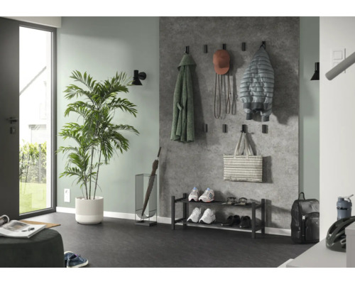 Moderner, organisierter Korridor mit Wandpaneelen in Betonoptik, schwarzen Garderobenhaken, Metall-Schuhregal, Schirmständer und grosser Zimmerpflanze.