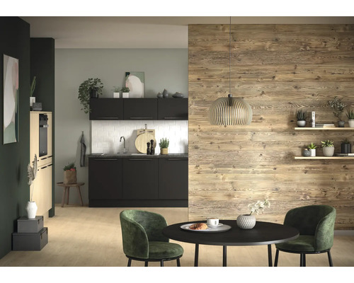 Moderne Küche mit schwarzen Elementen, weissem Plättlispiegel und Wandgestaltung in Holzoptik. Vorne ein runder schwarzer Tisch mit grünen Stühlen.