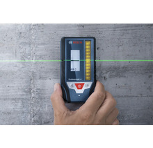 Récepteur laser Bosch Professional LR 7 contre un mur en béton avec une ligne laser verte horizontale.