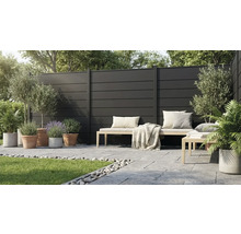 Brise-vue moderne composé de panneaux sombres sur une terrasse avec banc en bois, dalles en pierre et diverses plantes en pots.