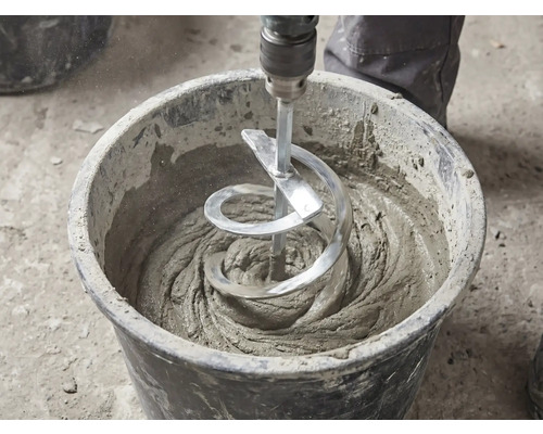 Un mélangeur à spirale mélange du mortier gris dans un seau de chantier noir.
