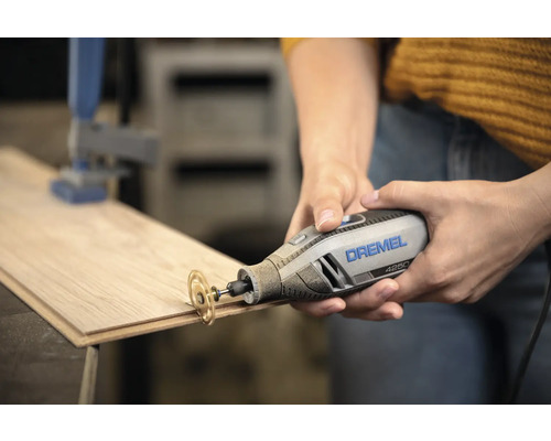 Outil multifonction Dremel 4250 avec disque à tronçonner coupant une planche en bois.