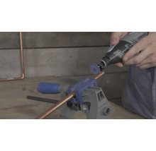 Un tube en cuivre fixé dans un étau est coupé avec un outil multifonction Dremel et un disque à tronçonner.