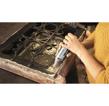 Une personne utilise un outil multifonction Dremel 4250 pour travailler sur un cadre en bois avec une grille métallique.