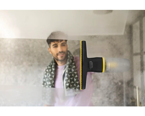 Un nettoyeur de vitres électrique élimine la condensation d'une surface vitrée dans une salle de bains, laissant une trace propre.