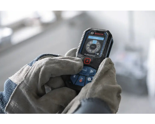 Télémètre laser Bosch Professional utilisé par des mains avec gants de travail, écran numérique avec fonctions de mesure.
