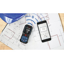 Télémètre laser Bosch avec connexion Bluetooth à une application smartphone sur un plan de construction.