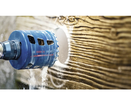 Scie cloche Bosch Expert Carbide Technology perçant un trou rond dans une surface texturée avec refroidissement par eau.