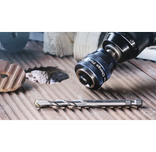 Adaptateur Power Change Plus sur une perceuse et un foret sur une surface en bois rainurée.