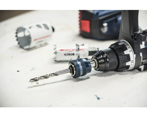 Adaptateur Bosch Power Change Plus avec foret de centrage monté sur une perceuse-visseuse à côté de scies-cloches.