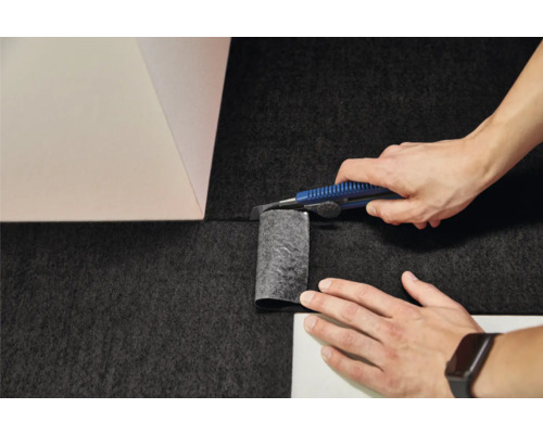 Pose de moquette : découpe du revêtement avec un cutter dans un angle de mur.