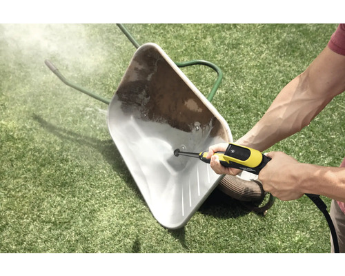 Nettoyage d'une brouette sale sur une pelouse avec un nettoyeur haute pression.