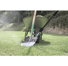 Un nettoyeur haute pression nettoie une pelle sale devant une brouette verte sur une pelouse.
