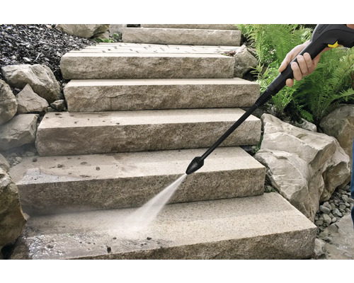 Nettoyage d'escaliers en pierre à l'extérieur avec le jet d'eau d'un nettoyeur haute pression.