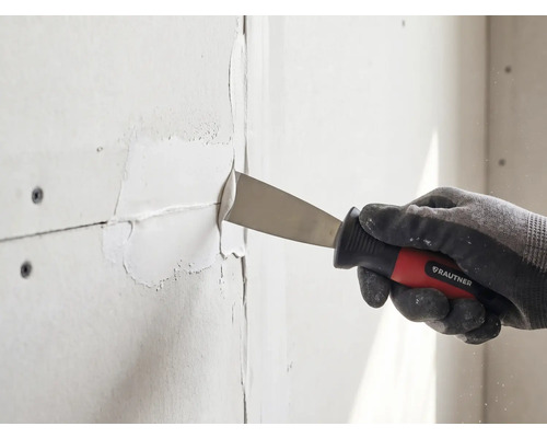 Hand mit Arbeitshandschuh nutzt eine Rautner Malerspachtel zum Verfugen von Gipskartonplatten.