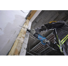 Un ouvrier utilise une scie sabre Bosch Professional pour couper une poutre en bois sur un chantier.
