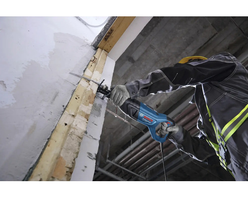 Un ouvrier utilise une scie sabre Bosch Professional pour couper une poutre en bois sur un chantier.