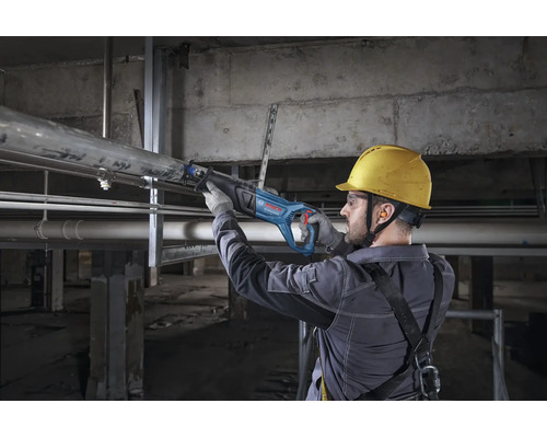 Artisan utilisant une scie sabre Bosch Professional pour couper un tuyau métallique sur un chantier.