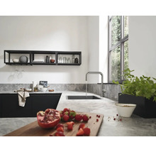 Cuisine moderne avec plan de travail gris clair aspect pierre, évier noir et robinet de cuisine en forme de U en acier inoxydable.