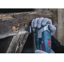Outil multifonction sans fil Bosch Professional GOP 18V-34 en train de couper du vieux bois avec un accessoire Starlock Plus.
