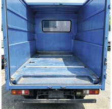 Espace de chargement vide d'un camion de transport avec des parois métalliques et une fenêtre dans la cloison.