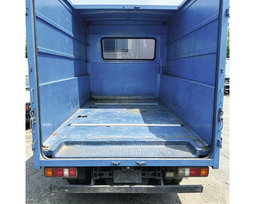 Espace de chargement vide d'un camion de transport avec des parois métalliques et une fenêtre dans la cloison.