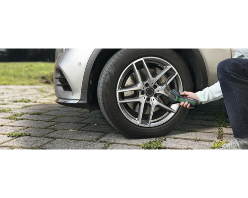 Eine Person pumpt mit der Bosch Akku-Druckluftpumpe EasyPump einen Autoreifen im Aussenbereich auf.