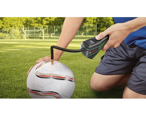 Bosch Akku-Druckluftpumpe beim Aufpumpen eines Fussballs auf einem Rasenplatz.