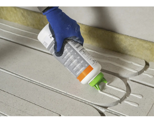 Main avec gant de travail appliquant de la colle thermique sur des plaques isolantes.