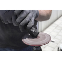 Nettoyage d'un disque de ponçage rotatif avec un bâton de nettoyage abrasif en caoutchouc.